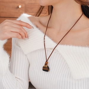 Close-up of a vintage leather necklace with a bag-shaped stone pendant and gold accents