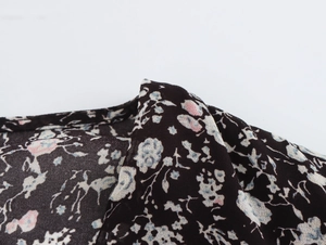 Close-up of black floral chiffon fabric detail showing elegant petal pattern and texture