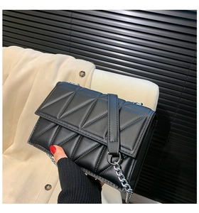 Detail of black quilted leather crossbody bag with silver chain strap and shoulder pad
