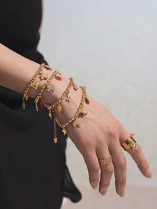 Detail eines goldenen Bambusketten-Armbands mit Herz-, Kleeblatt- und Marienkäfer-Anhängern