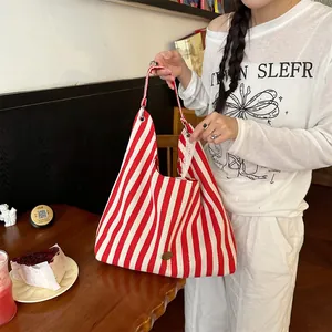 Détail du sac cabas en toile à rayures rouges et blanches avec poignées renforcées au café