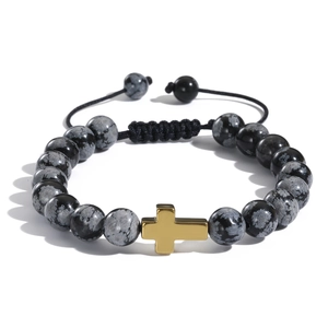 Dettaglio del bracciale intrecciato con perle di ossidiana fiocco di neve e croce dorata