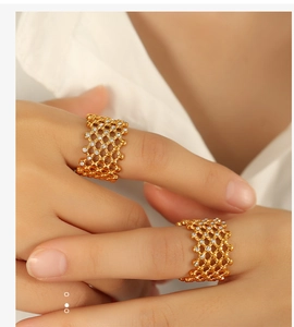 Close-up of golden honeycomb rings with sparkling crystals on a hand