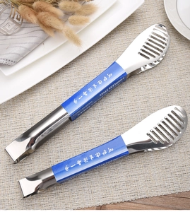 Macro view of polished stainless steel food tongs on a woven mat with minimalist decor