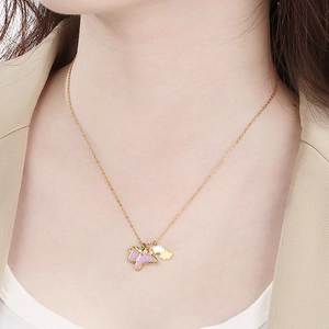 Gros plan d'un collier doré avec pendentif papillon rose et nuage sur un mannequin