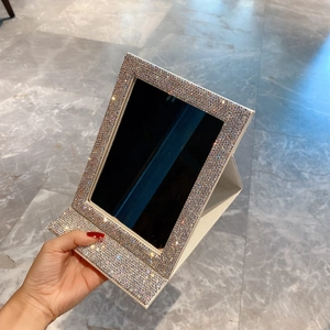 Close-up of portable folding makeup mirror featuring colorful rhinestones on silver frame