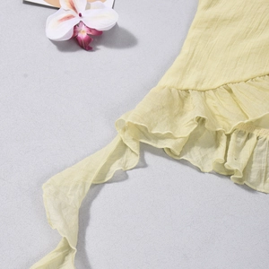 Detail of light yellow ruffle trim with delicate pleated texture and floral accent