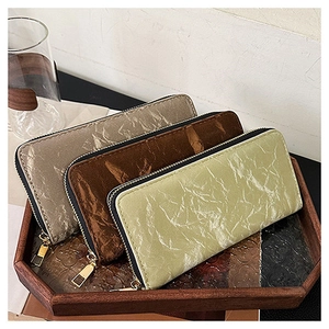 Detailed view of long zip wallets in pleated leather texture with three elegant colors