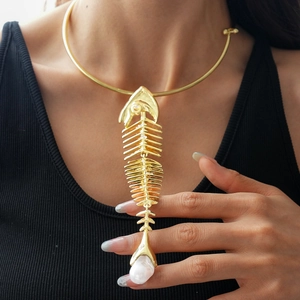 Detailed close-up of a golden fishbone pendant necklace with an irregular baroque pearl