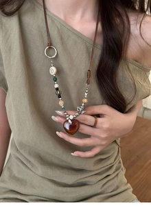 Close-up of vintage beaded long necklace with amber heart pendant on a model