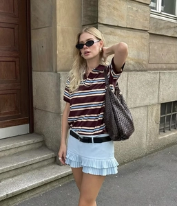Dettaglio in stile urban di una polo retrò a righe e una gonna a pieghe blu all'aperto