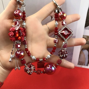 Detail of beaded bag charm with red crystal, rose floral accents and Xi character pendant