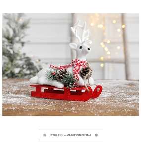 Detail of white flocked reindeer with a red scarf on a festive wooden red sled base