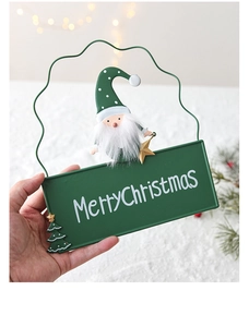 Detailed view of hand-held Merry Christmas metal door sign with Santa and tree motifs