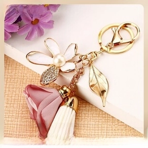 Detail view of floral keychain with white flower, pink silk rose and golden leaf charm