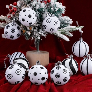 Detail of black and white patterned Christmas ball ornaments with silver caps on velvet base