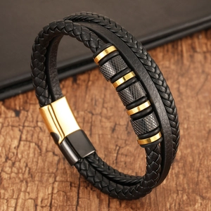 Detail of black braided leather bracelet with gold magnetic clasp on dark wood