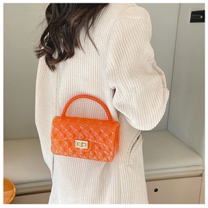 Orange PVC jelly bag with pearl handle and metal lock shown in a lifestyle setting