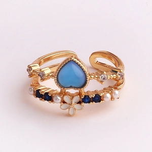 Detail of double-layer open ring featuring blue heart stone and enamel flowers