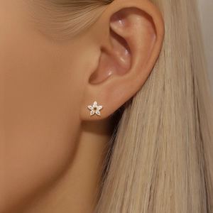 Detail shot of five-petal flower silver stud earring with clear teardrop zircon on ear