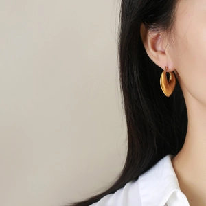Close-up of chunky gold teardrop hoop earrings with a high-polished mirror finish