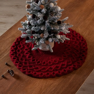Jupe de sapin de Noël tricotée rouge avec motif crocheté sur une table en bois rustique