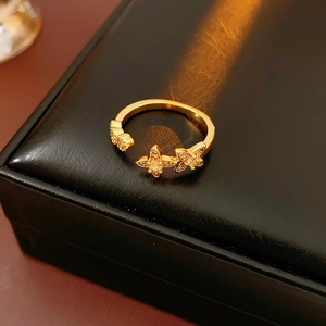 Nahaufnahme eines goldenen Vintage-Rings mit Zirkonblüten und Schmetterlingen auf einer Box