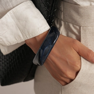 Détail d'un bracelet en résine bleu foncé à motif marbré sur le poignet d'un mannequin