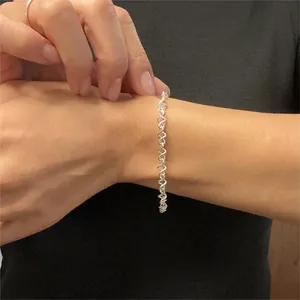 Macro shot of 925 sterling silver twisted chain bracelet on wrist with heart wave design