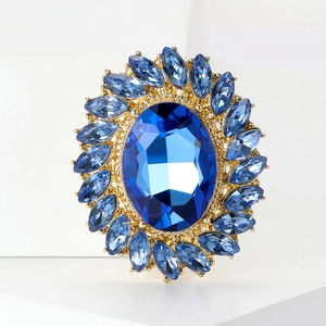 Close-up of vintage golden brooch with central blue oval stone and rhinestone petals