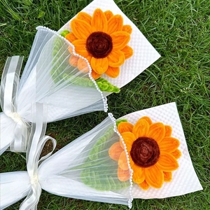 Close-up of handmade yellow sunflower bouquet with lace wrapping on green grass