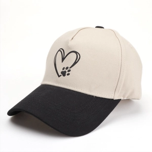 Détail de l'imprimé cœur et patte sur la casquette de baseball beige et noire avec panneau