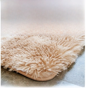 Detailed view of extra long beige plush rug texture with high density and woven edges