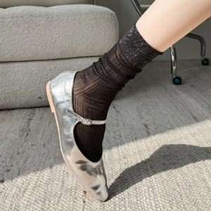 Close-up of silver Mary Jane shoes with metallic finish and sheer black socks