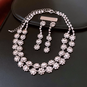 Close-up of sparkling crystal floral necklace and earring set on black leather background