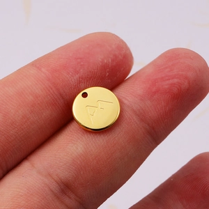 Polished 18K gold plated stainless steel mountain pendant held between fingers