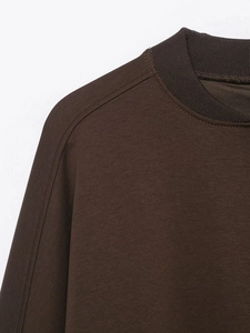 Detail of deep brown ribbed crewneck collar and double stitching on cotton fabric