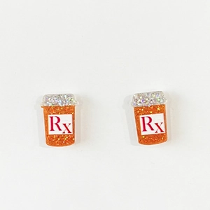 Macro detail of orange glitter medicine bottle earrings with red Rx medical symbol