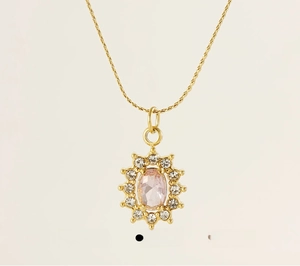 Macro detail of sunflower pendant necklace with pink zircon stone in polished gold steel