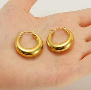 Macro shot of 18K gold plated chunky hoop earrings held in hand to show size and luster