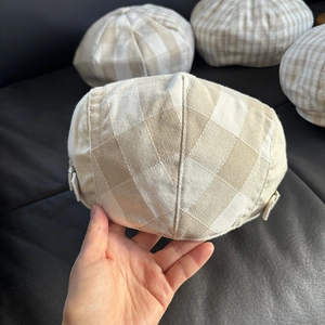 Detailed view of linen plaid newsboy cap with adjustable metal side buckle and checkered pattern
