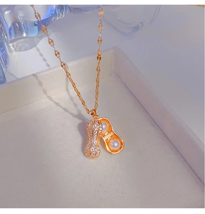 Détail macro du pendentif cacahuète doré avec pavé de cristaux et perles blanches