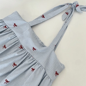 Detail of blue striped tote bag featuring red bow embroidery and drawstring ribbon
