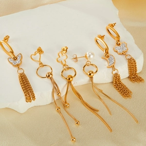 Golden tassel earrings set with butterfly heart and pearl pendants on white stone