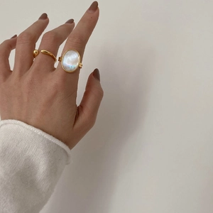 Close-up of golden ball open ring and vintage oval iridescent mother of pearl ring