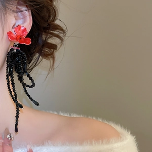 Détail de boucles d'oreilles fleur rouge vintage avec pompons perlés noirs sur mannequin