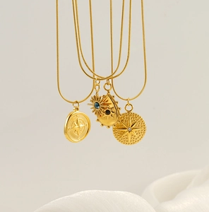 Detail of tarot necklaces featuring gold compass and star pendants on snake chains