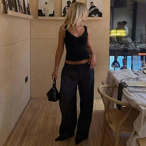 Gros plan d'un débardeur noir avec bordure en dentelle porté par un mannequin au café