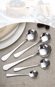 Macro detail of five polished stainless steel round spoons in varied sizes on a placemat