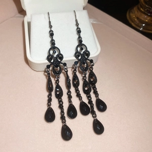 Macro view of vintage hollow-out drop earrings with elegant black chain tassels